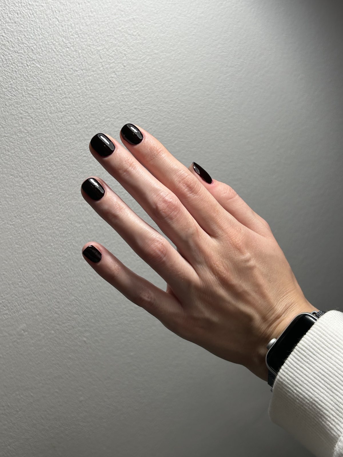 Elegancki ciemny, prawie czarny manicure na jasnym tle